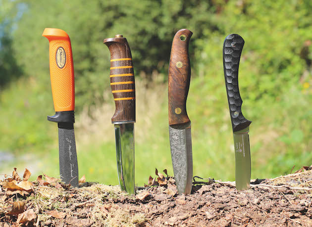 Four fixed blade hunting knives standing in the ground between jobs
